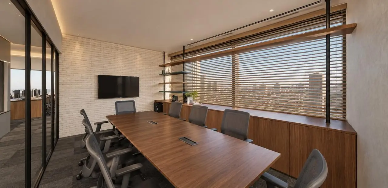 Sala de reunião da Qoros Capital, com mesa de madeira e vista da cidade